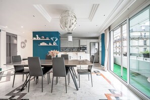 A modern dining area with a large table, chairs, and a decorative ceiling light.
