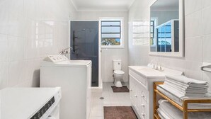A modern bathroom with a toilet, sink, and bathtub. - Vincentia Breeze by Experience Jervis Bay (Vincentia)