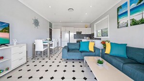 A modern apartment with a dining area, kitchenette, and living room. - Vincentia Breeze by Experience Jervis Bay (Vincentia)