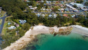 Vista aérea de uma área residencial costeira, com casas, ruas e uma praia.