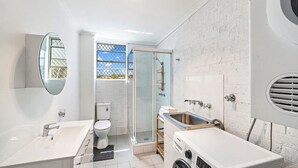 Une salle de bain moderne avec une douche à parois de verre, un lavabo blanc et des toilettes.