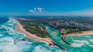 An aerial view of a coastal town with a beach, a river, and residential areas. - Ocean Outlook 2 on Marine Parade (KINGSCLIFF)