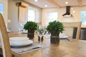 A dining table set with white plates, a wine glass, and two small potted plants.