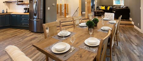 A dining area with a wooden table set for six, surrounded by chairs.
