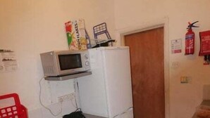 A compact kitchen with a microwave, refrigerator, washing machine, and a small sink. - London Airport Comfort (London)