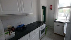 A kitchen with white cabinets, a black countertop, and a window with a view. - London Airport Comfort (London)
