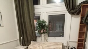 A neatly arranged bedroom with a bed, bedside tables, a nightstand, a dresser, and a window with curtains. - London Airport Comfort (London)