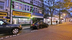 A street view with a building labeled 'Vida & Sons Shop' and a car parked on the side. - London Airport Comfort (London)