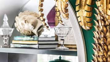 A room with a large mirror, a green vase, and books on a shelf.