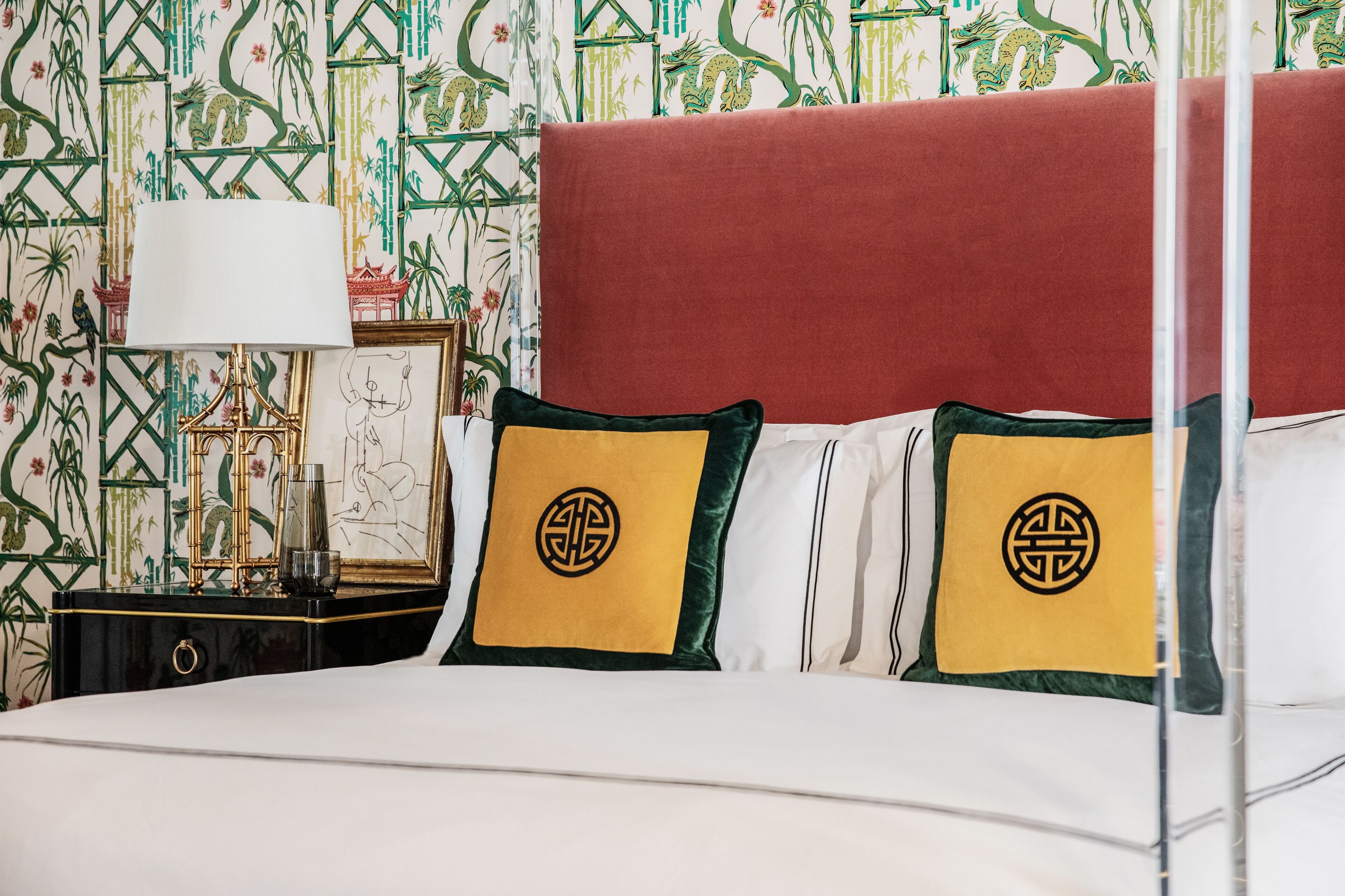 A neatly made bed with white linens and two pillows with a geometric design.
