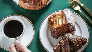 Ett bord med croissanter, en brödskiva och en kopp kaffe.