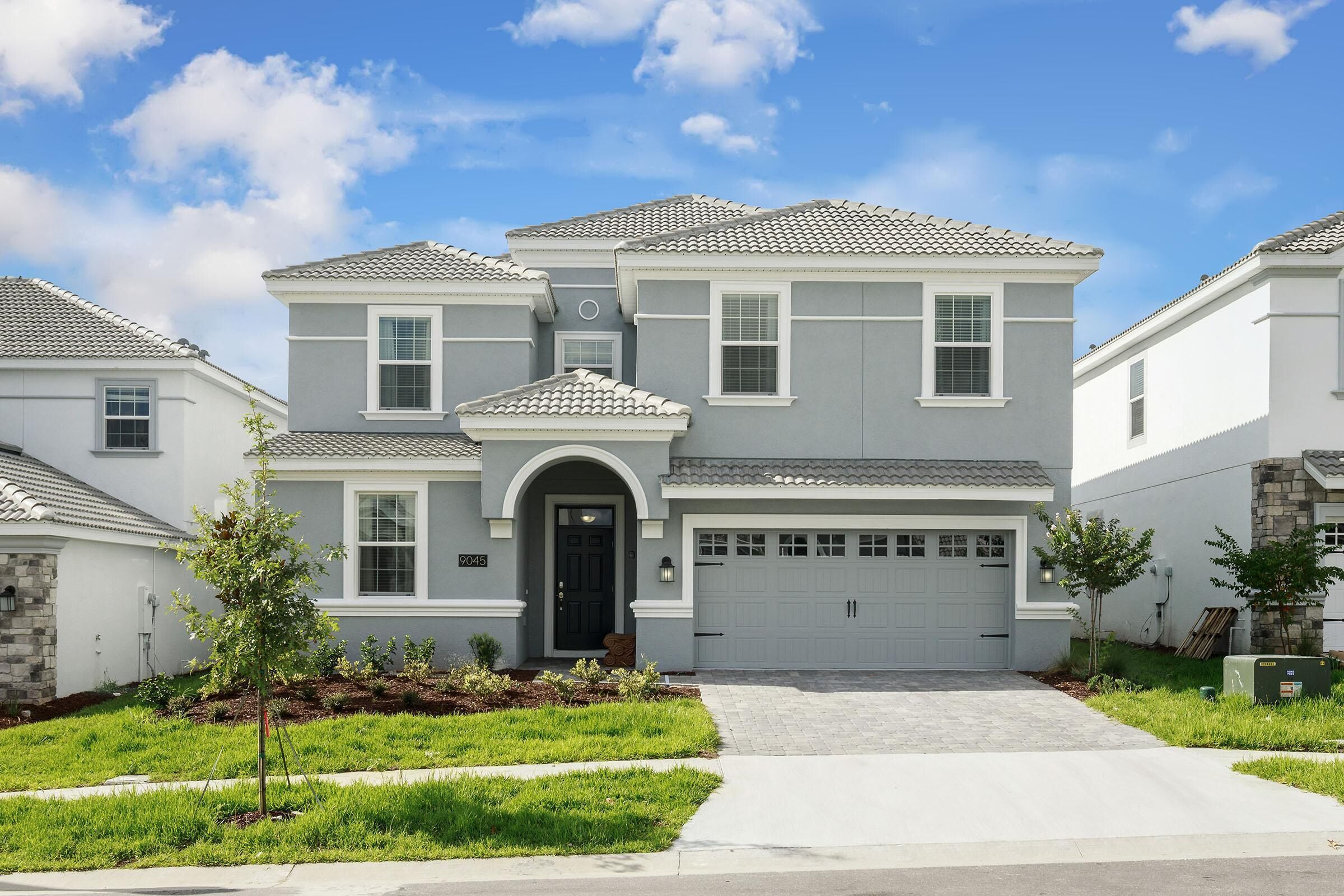 A two-story residential house with a garage, a driveway, and a well-maintained lawn.