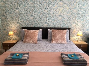 Un lit avec une tête de lit à motifs, deux lampes de chevet et un mur décoratif.