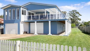 Een twee verdiepingen tellend huis met een balkon, garage en een witte picket fence.