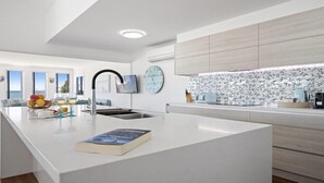Een moderne keuken met een centraal eiland, een inbouwspoelbak en een grote klok aan de muur.