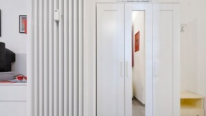 Un armario blanco con dos puertas, un estante blanco y un mueble de almacenamiento blanco.