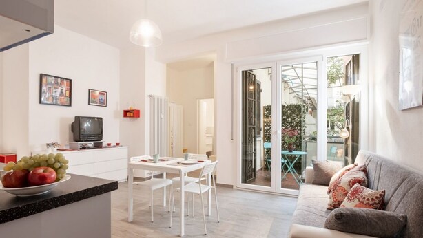 Cocina moderna con comedor, sofá y puerta corrediza de vidrio que da a un espacio exterior.