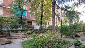 Un patio con un banco, plantas en macetas y un edificio de fachada de ladrillo.