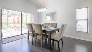 A dining area with a dark wooden table, six upholstered chairs, and a hanging light fixture.