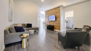 A modern living room with a grey sofa, a black armchair, and a wooden accent wall.