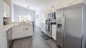 A modern kitchen with white cabinetry, stainless steel appliances, and a central island.