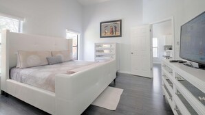 A bedroom with a bed, a dresser, a television, and a painting on the wall.