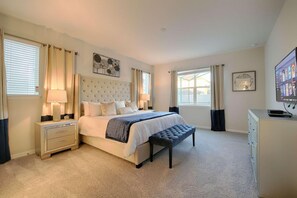A bedroom with a large bed, bedside tables, a bench, a TV, and artwork on the walls. - 9009 Solara (Kissimmee)