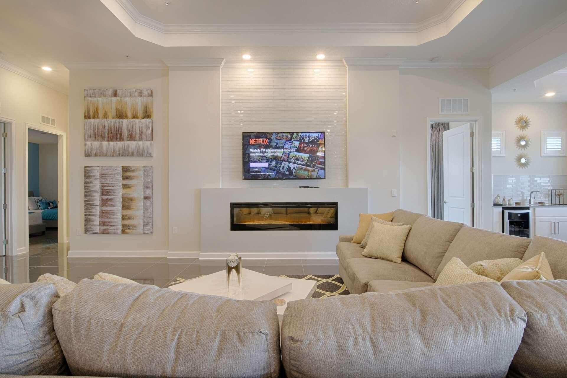 A living room with a fireplace, a television mounted above it, and a sofa with cushions.