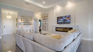 Ein modernes Wohnzimmer mit einer großen Eckcouch, einem Kamin und einem Wand-Fernseher.
