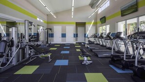 Een sportschool met loopbanden, krachtapparaten en een spiegelwand.