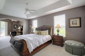 A bedroom with a large bed, a ceiling fan, a dresser, a lamp, and a window. - 625 Highlands Reserve (Davenport)