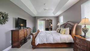 Ein Schlafzimmer mit einem großen Bett, einer Holzkommode und einem Fernseher.