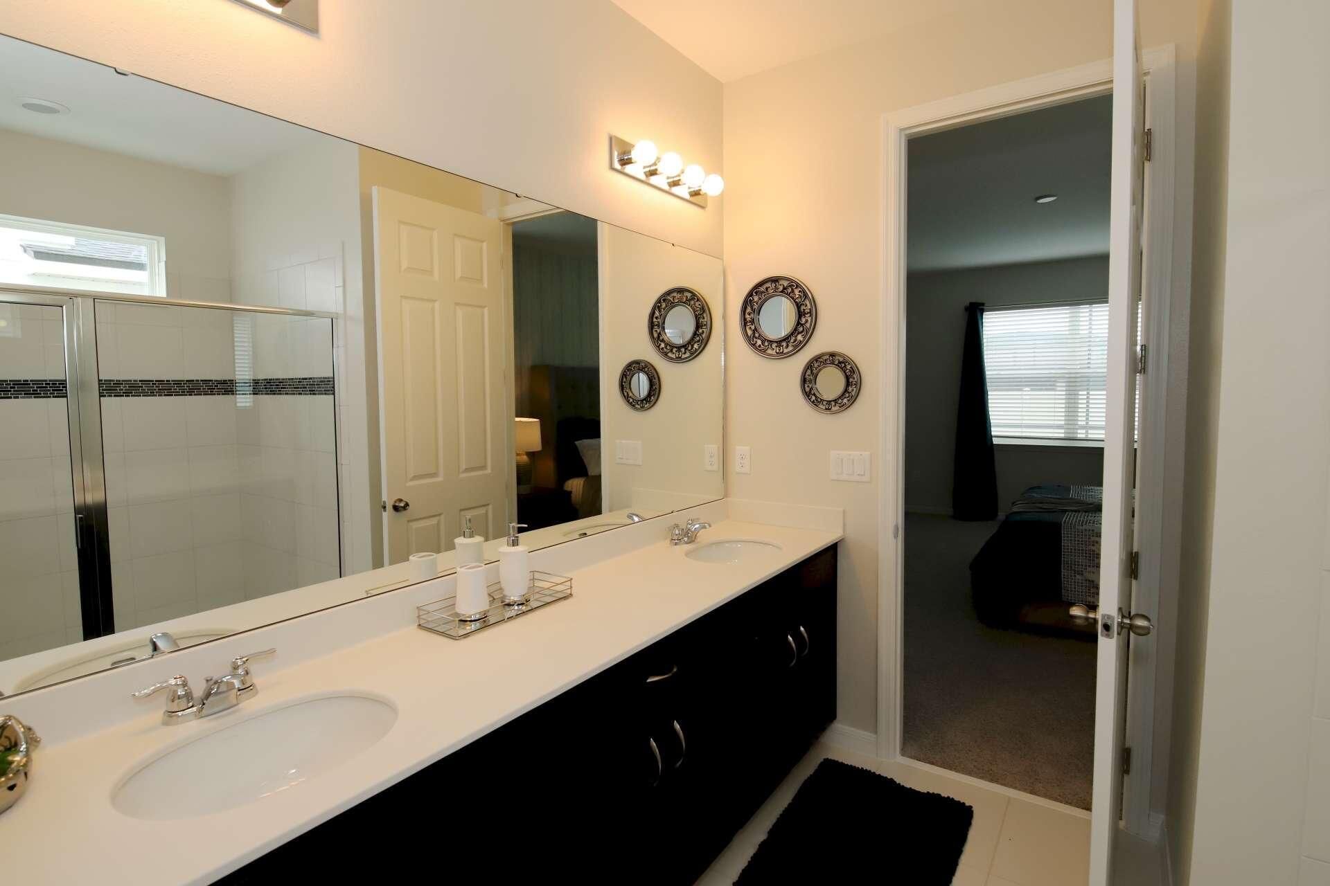 A modern bathroom with a large mirror, two sinks, and decorative wall mirrors.