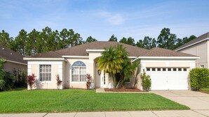 A single-story house with a garage, a front lawn, and a palm tree. - 600 Highlands Reserve (Davenport)
