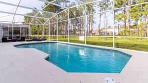 A swimming pool with a glass enclosure, surrounded by lounge chairs and a grassy area with trees. - 600 Highlands Reserve (Davenport)