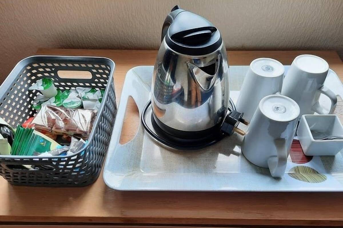 Ett bricka med en kaffebryggare, koppar och en korg med snacks på ett träbord.