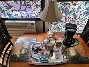 A dining table with a tray containing a coffee maker, a bottle, and some food items. - Great House Motel (Sequim)