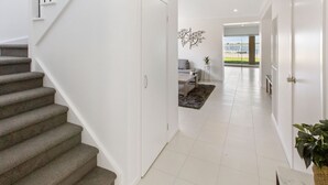 A modern hallway with a staircase, a living area with a sofa and coffee table, and a view of the outdoors.