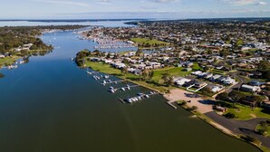 An aerial view of a lakeside residential area with a marina, houses, and green spaces.