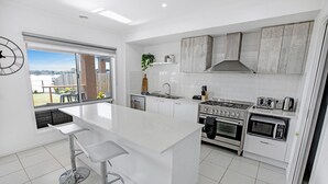 A modern kitchen with a large island, white cabinetry, and a view of the outdoors.