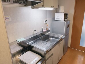 A compact kitchen with a microwave, a built-in oven, a sink, and a dish rack.