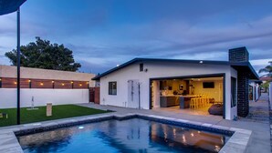 A modern house with a swimming pool, a kitchen, and a dining area.