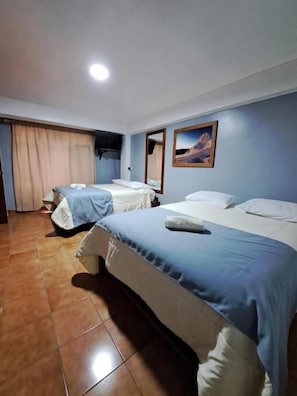 A hotel room with two beds, a flat-screen TV mounted on the wall, and a painting above the beds. - Alpamayo Guest House (Huaraz)