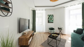 Una sala de estar moderna con televisor de pantalla plana, una mesa de centro de madera y un sofá verde.