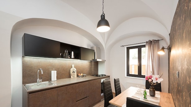 Una cocina moderna con horno empotrado, un lavamanos y una zona de comedor con mesa y sillas.