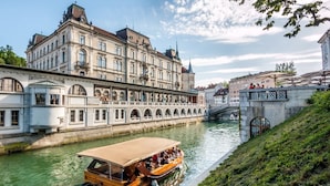Un edificio histórico con ubicación frente al río, servicio de paseos en barco y un puente peatonal.