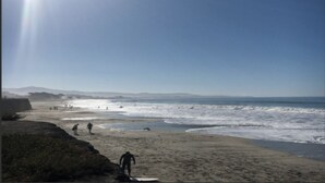 A beach with people walking and surfing, a clear sky, and distant hills. - Private Studio , spectacular  Ocean View , bathroom , kitchenette, Very Quiet (Half Moon Bay)