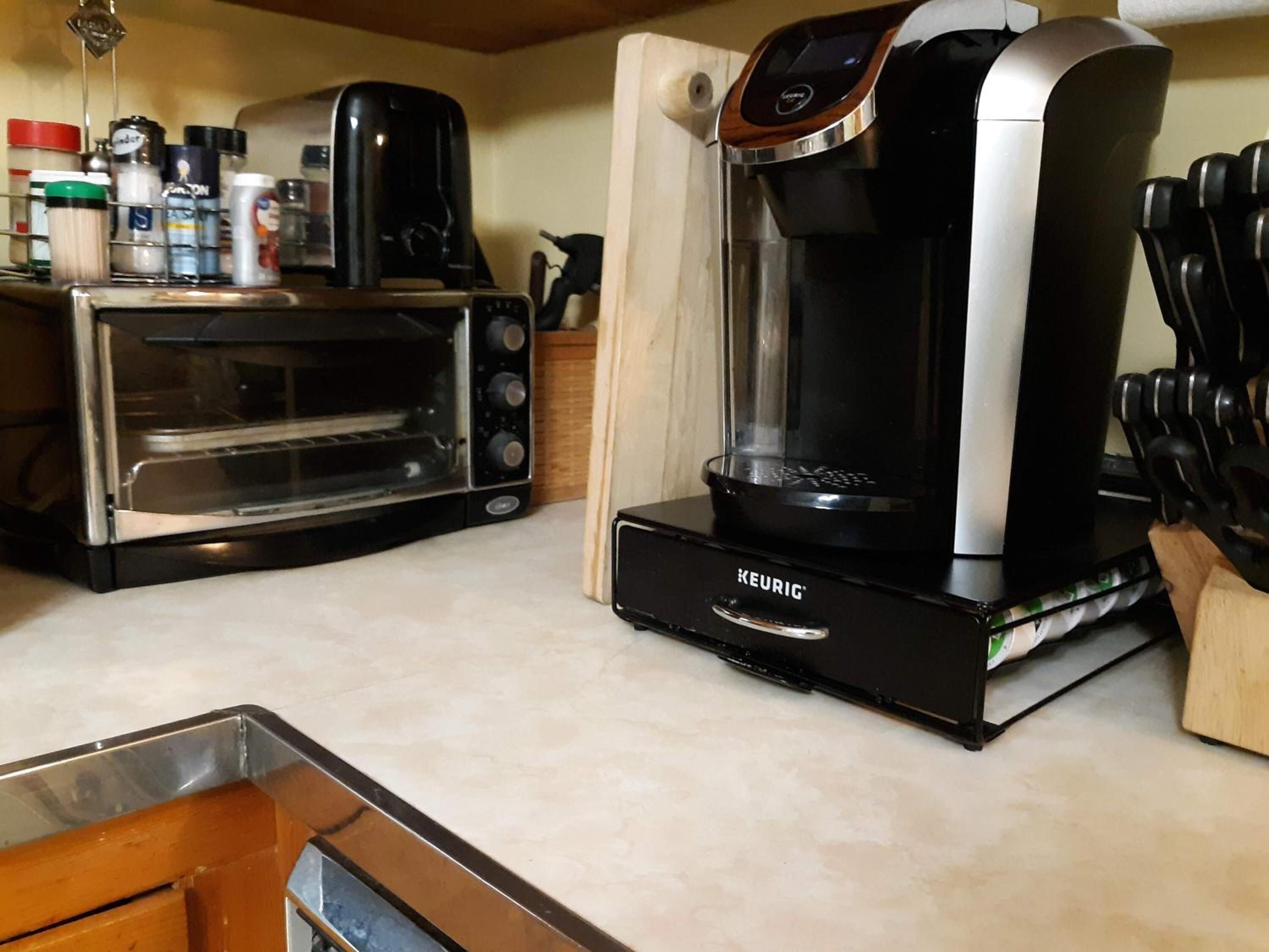Une petite cuisine équipée d’une machine à café Keurig, d’un four grille-pain et de divers ustensiles de cuisine.