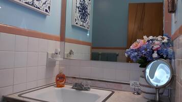 Ein Badezimmer mit Waschbecken, Spiegel und einer Zierblumenkomposition.