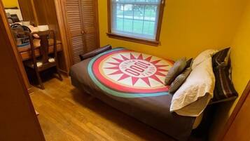 A small, cozy bedroom with a bed, a window, and a wooden wardrobe.